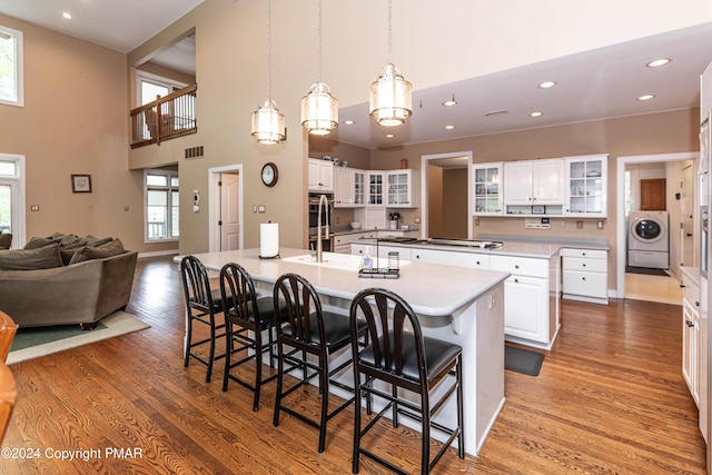 kitchen with a breakfast bar, wood finished floors, washer / clothes dryer, and a kitchen island with sink