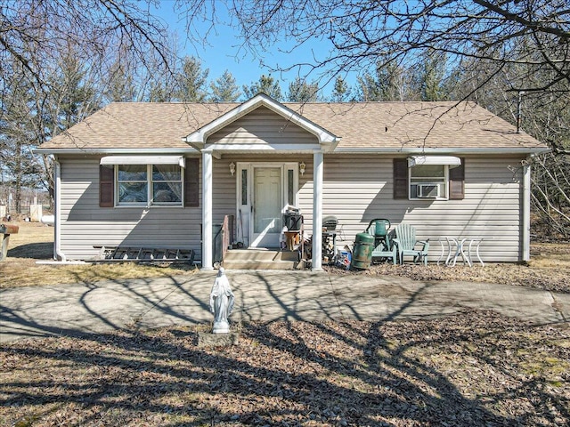 view of front of house featuring cooling unit, driveway, and roof with shingles