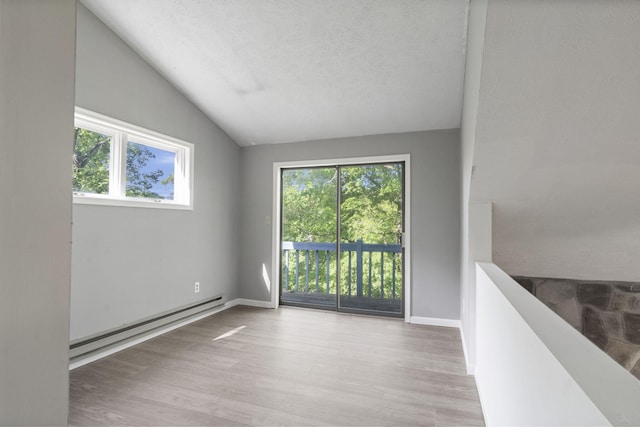 6471 Decker Rd, Bushkill, PA 18324 - unfurnished room featuring baseboard heating, plenty of natural light, lofted ceiling, wood finished floors, and a textured ceiling