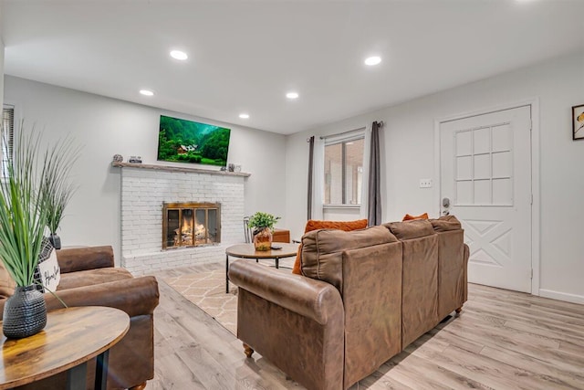 living area with recessed lighting, light wood-style floors, and a brick fireplace