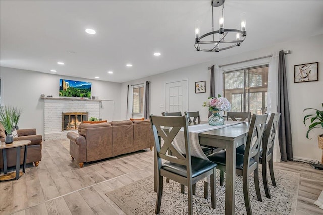 dining space featuring recessed lighting, light wood-type flooring, a notable chandelier, and a fireplace