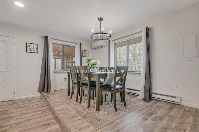 dining room featuring an inviting chandelier, a wall unit AC, baseboards, and light wood-type flooring