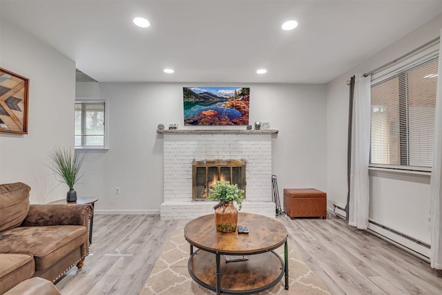 living area featuring light wood-style flooring, recessed lighting, a baseboard radiator, baseboards, and a brick fireplace