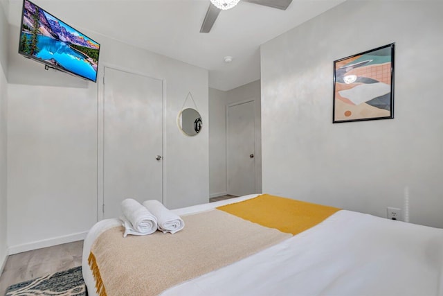 bedroom with a ceiling fan, wood finished floors, and baseboards