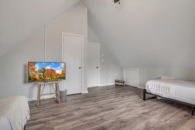 bedroom with vaulted ceiling, wood finished floors, and baseboards