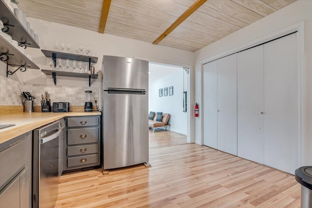 kitchen with light wood-type flooring, gray cabinetry, backsplash, stainless steel appliances, and wooden ceiling