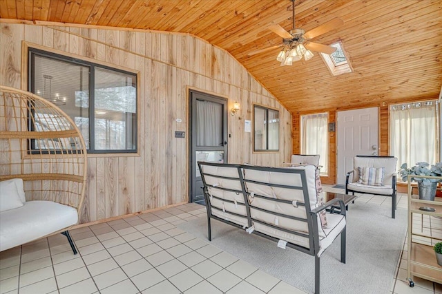 interior space with lofted ceiling with skylight, wood ceiling, a ceiling fan, and a healthy amount of sunlight