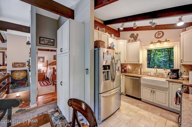 kitchen featuring sink, white cabinetry, light stone counters, appliances with stainless steel finishes, and backsplash