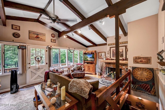 living room featuring ceiling fan, a fireplace, rail lighting, and vaulted ceiling with beams