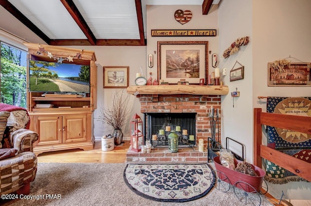 living room featuring a brick fireplace, hardwood / wood-style flooring, and lofted ceiling with beams