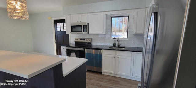 kitchen with stainless steel appliances, a sink, decorative backsplash, and wood finished floors