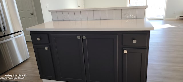 kitchen featuring light countertops, light wood finished floors, and freestanding refrigerator