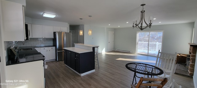 kitchen with dark wood-style flooring, tasteful backsplash, freestanding refrigerator, a kitchen island, and a sink