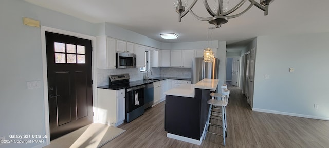 kitchen with a sink, white cabinetry, appliances with stainless steel finishes, tasteful backsplash, and a kitchen bar