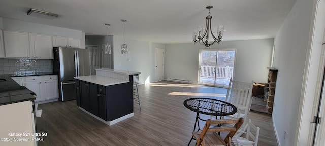 kitchen with dark wood-type flooring, hanging light fixtures, backsplash, freestanding refrigerator, and a center island