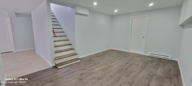 basement featuring baseboards, stairway, wood finished floors, a baseboard heating unit, and recessed lighting