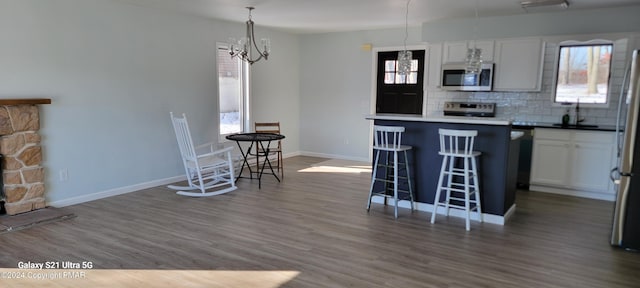 kitchen with appliances with stainless steel finishes, a breakfast bar, dark wood finished floors, and decorative backsplash