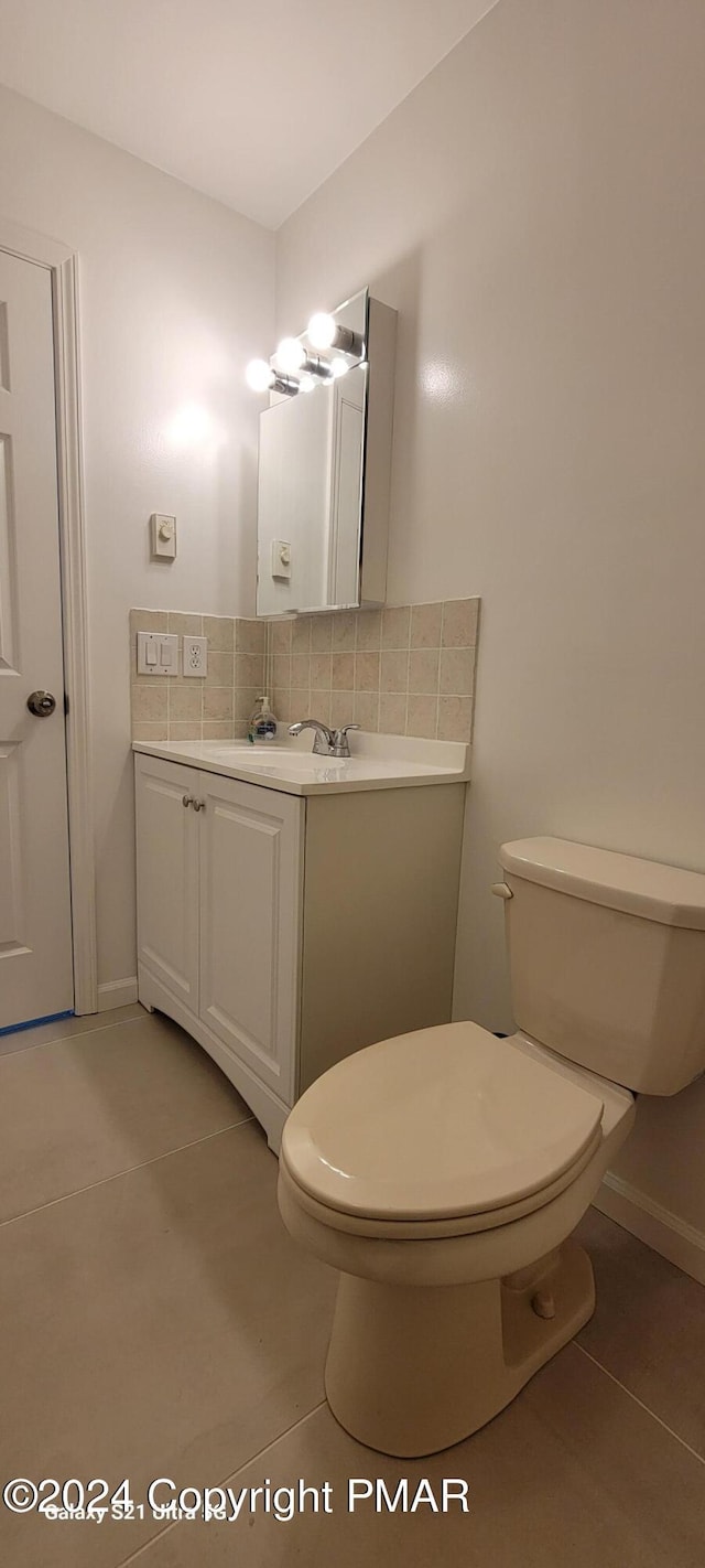 half bath featuring vanity, tile patterned floors, toilet, and decorative backsplash