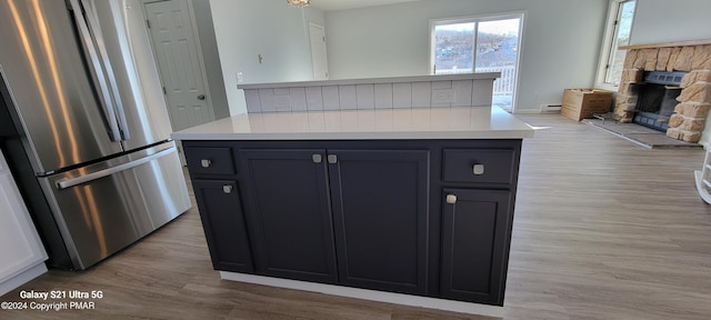 kitchen with a fireplace, light countertops, light wood-style floors, freestanding refrigerator, and open floor plan