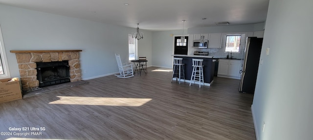 unfurnished living room featuring dark wood-style floors, a fireplace, baseboards, and a chandelier