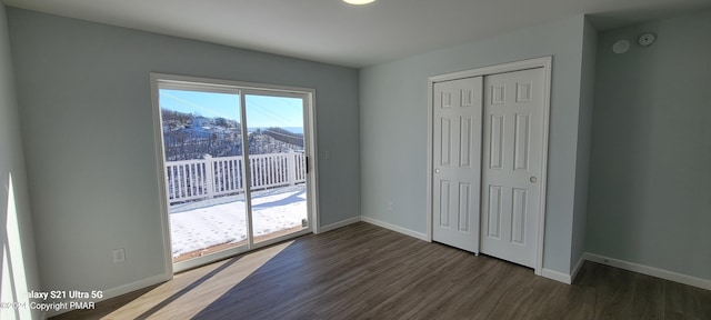 unfurnished bedroom with access to outside, a closet, baseboards, and wood finished floors