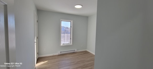 empty room with a baseboard radiator, baseboards, and wood finished floors