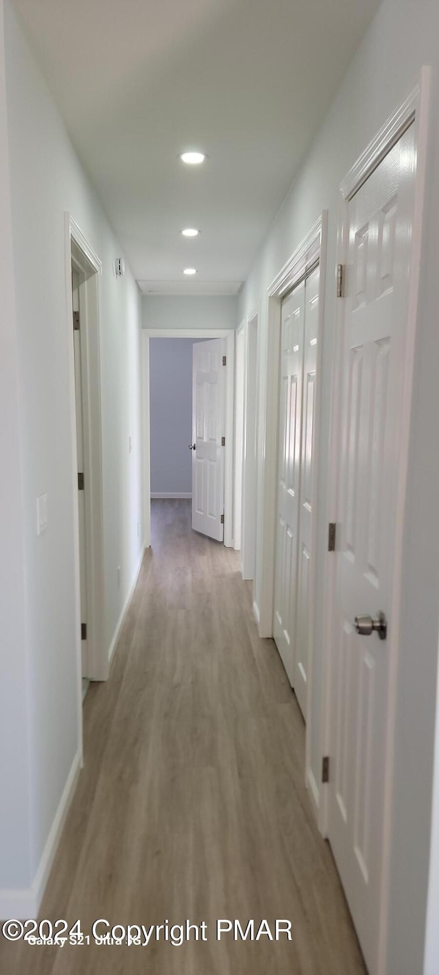 hall featuring baseboards, recessed lighting, and light wood-style floors