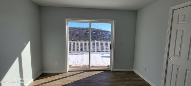 doorway to outside featuring baseboards and wood finished floors