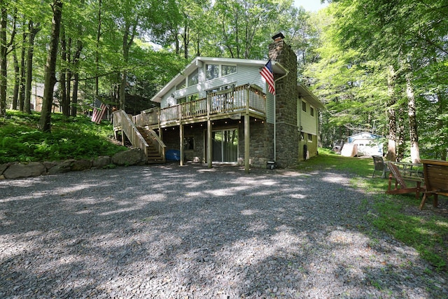 354 Fawn Rd, Pocono Lake, PA 18347 - view of front facade with a deck, stairs, stone siding, a chimney, and driveway