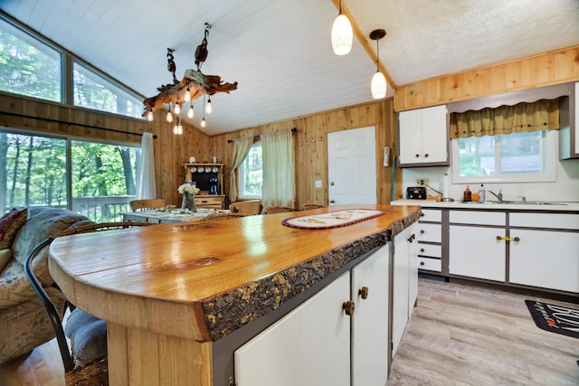354 Fawn Rd, Pocono Lake, PA 18347 - kitchen with plenty of natural light, white cabinetry, light wood-type flooring, vaulted ceiling, and wood walls