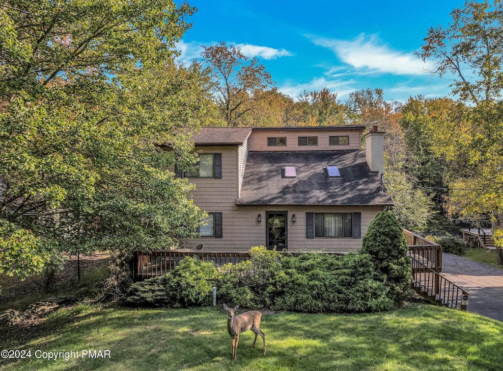 view of front of property featuring roof with shingles, a chimney, and a front yard