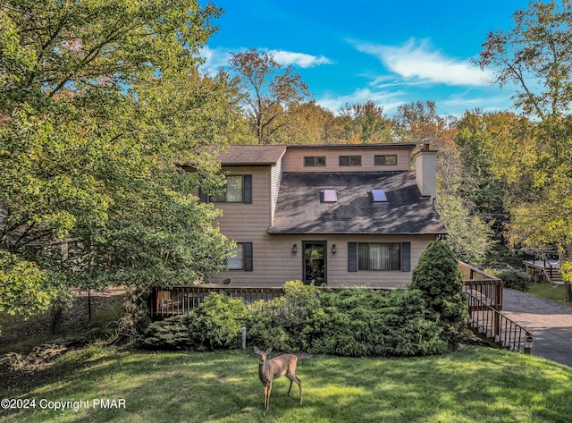 view of front of property featuring roof with shingles, a chimney, and a front yard