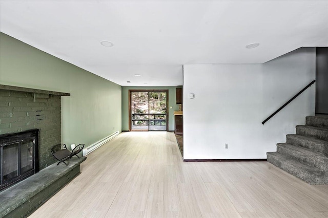 6061 Decker Rd, Bushkill, PA 18324 - unfurnished living room featuring baseboard heating, wood finished floors, stairway, a brick fireplace, and baseboards