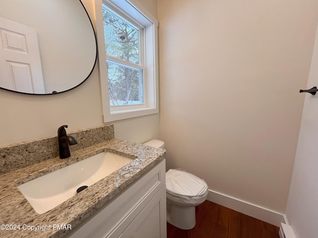 bathroom with toilet, baseboards, wood finished floors, and vanity