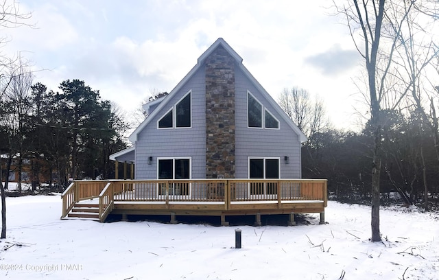 snow covered house featuring a chimney and a deck