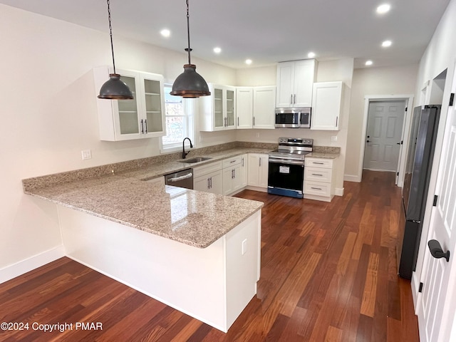 kitchen with appliances with stainless steel finishes, glass insert cabinets, a sink, light stone countertops, and a peninsula