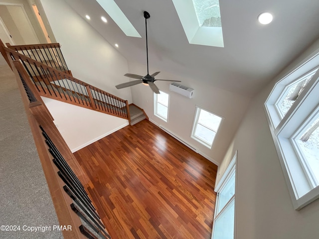 unfurnished living room featuring plenty of natural light, a towering ceiling, and wood finished floors