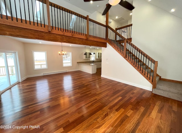 unfurnished living room featuring a baseboard heating unit, stairway, dark wood-style floors, and baseboards