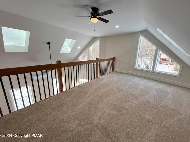 additional living space with vaulted ceiling with skylight, carpet flooring, a ceiling fan, and baseboards