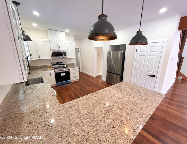 kitchen featuring stainless steel appliances, light stone countertops, white cabinetry, and dark wood-style floors