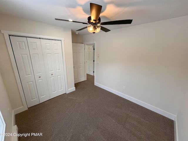 unfurnished bedroom featuring a ceiling fan, baseboards, dark carpet, and a closet