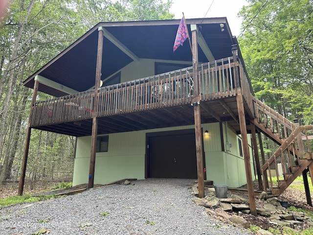 view of front facade featuring gravel driveway, stairway, a wooden deck, a garage, and a carport