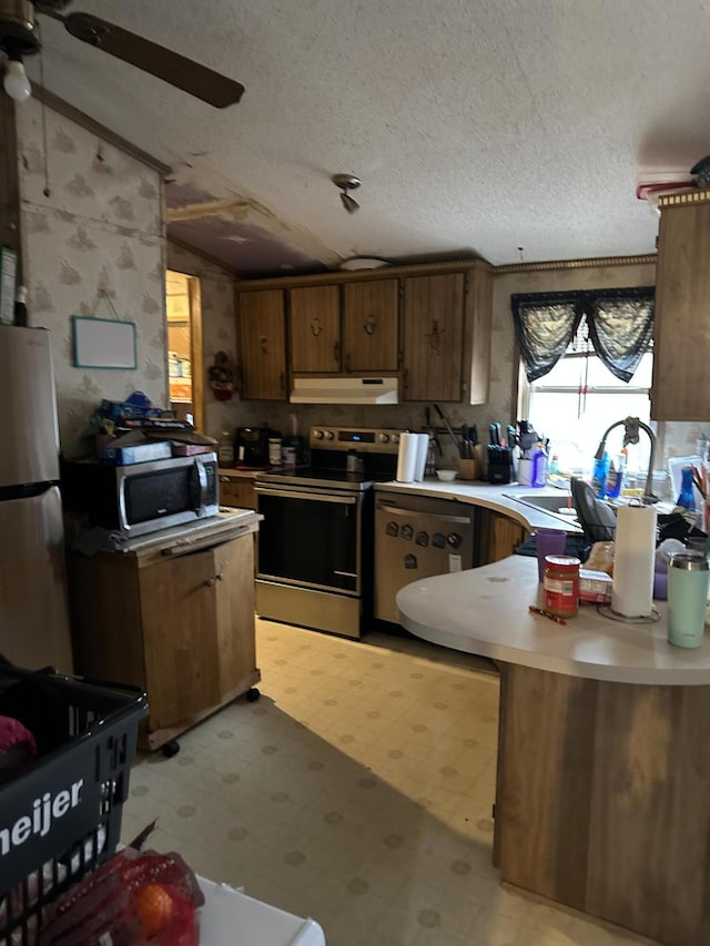 3175 Pocono Dr, East Stroudsburg, PA 18302 - kitchen featuring a ceiling fan, under cabinet range hood, stainless steel appliances, light countertops, and light floors