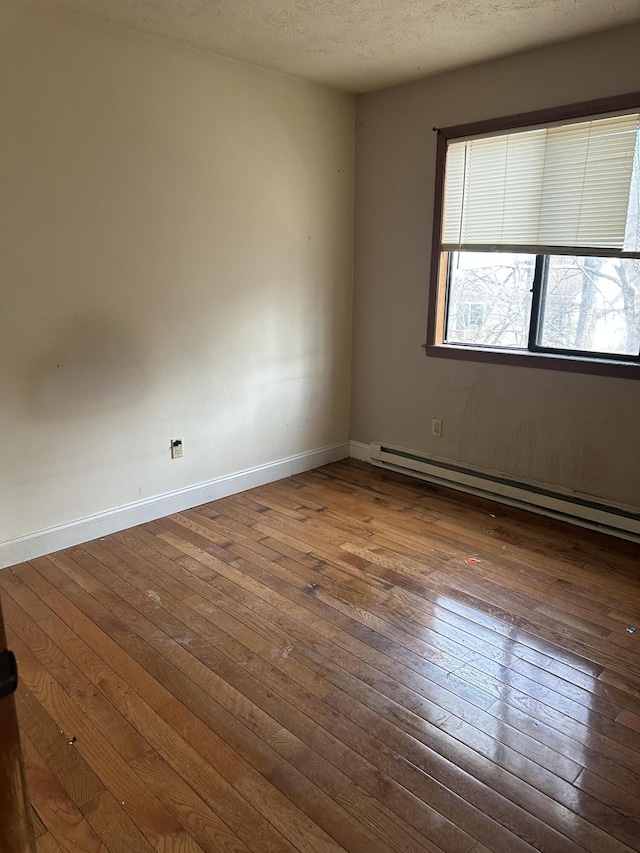 unfurnished room with wood-type flooring, baseboards, baseboard heating, and a textured ceiling