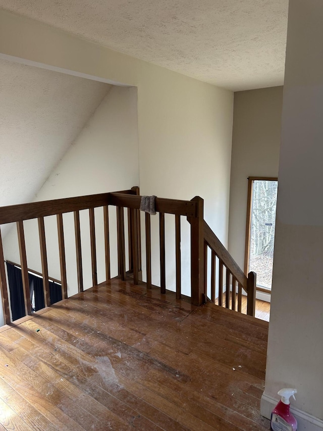 staircase featuring a textured ceiling and hardwood / wood-style flooring