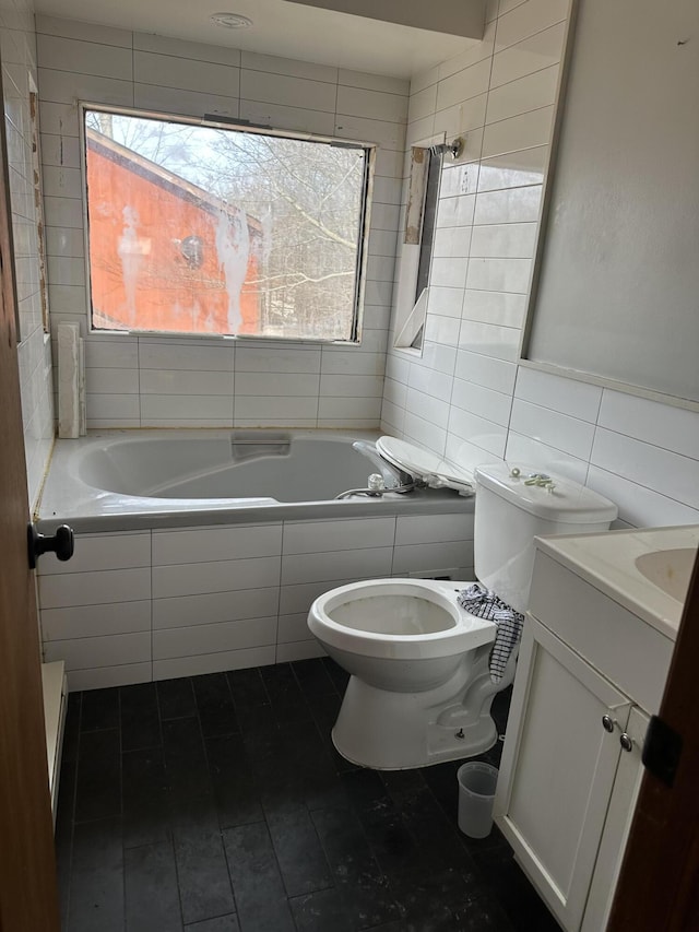 full bath with tiled bath, tasteful backsplash, toilet, vanity, and tile walls