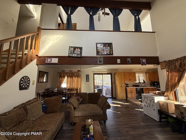 living area with dark wood-style floors, stairs, and a towering ceiling