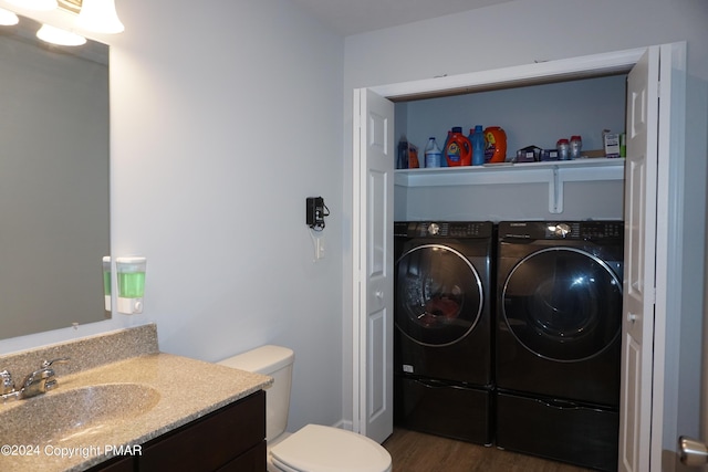 bathroom featuring vanity, toilet, separate washer and dryer, and hardwood / wood-style floors