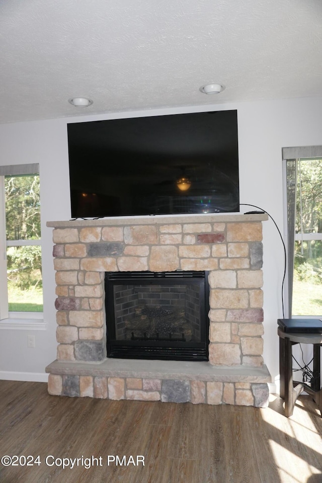 interior details with a stone fireplace, wood-type flooring, and a textured ceiling