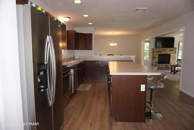 kitchen with a breakfast bar, pendant lighting, a center island, stainless steel refrigerator with ice dispenser, and dark wood-type flooring